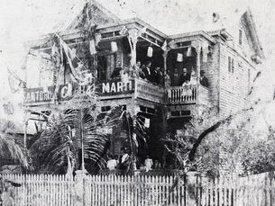 A group of people on the second story porch of a wooden home