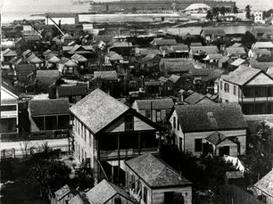 Aerial view of buildings with a fort and battleship on the horizon