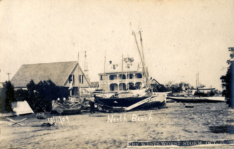 Wrecked boats on land in front of building. Text on image reads 10/11/09 North Beach and Key West's Worst Storm Oct. 11 1909