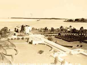 Aerial view of a building on a shoreline with a hedge maze and pool