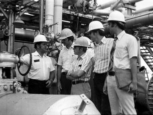 A group of men wearing hard hats inside an industrial facility.