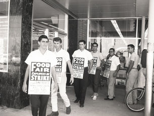 Men on a picket line in front of a store, carrying signs that say Food Fair Employees on Strike.