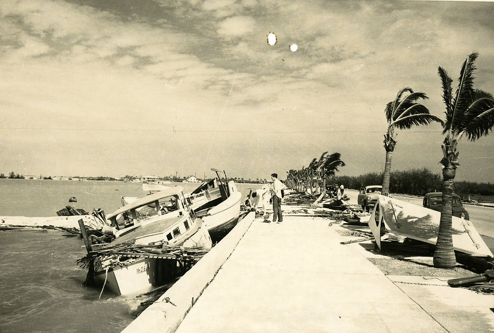 People on a seawall with wrecked boats alongside