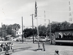 Boy Scouts raise an American flag while other people look on