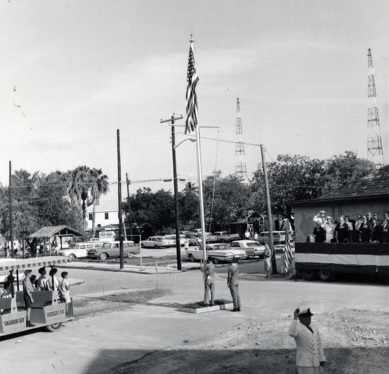 Boy scouts raise an American flag while other people look on.