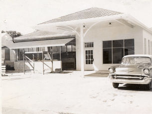 A 1950s style car in front of a service station style building