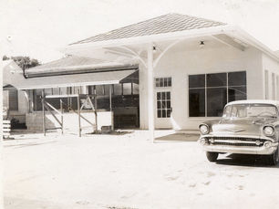 A 1950s style car in front of a service station style building