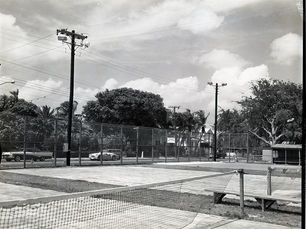 Tennis courts behind a fence next to a street