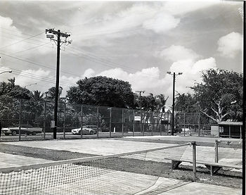 Fenced tennis courts on a street.