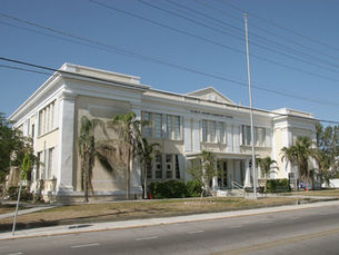 a large light yellow building with a flag pole out front