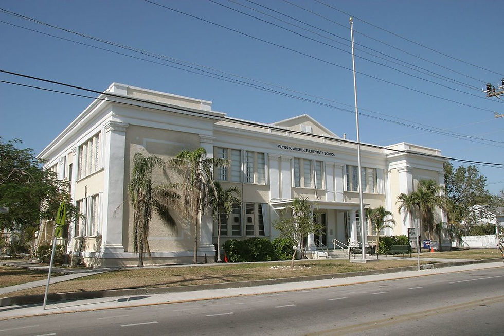 A large light yellow building with a flag pole out front.