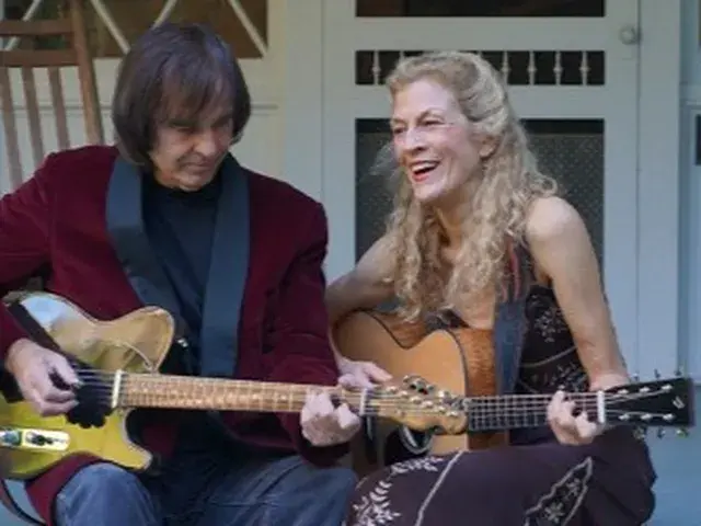 two people play guitars