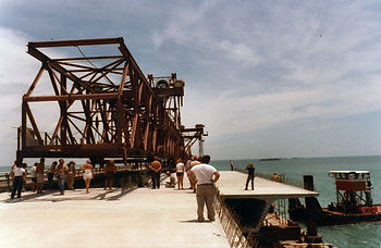 People standing in front of truss section on a bridge.