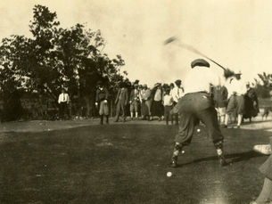 A man swings a golf club while watched by a group of people