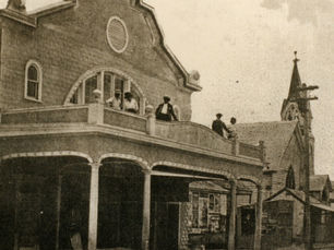 people standing on a balcony over a sidewalk