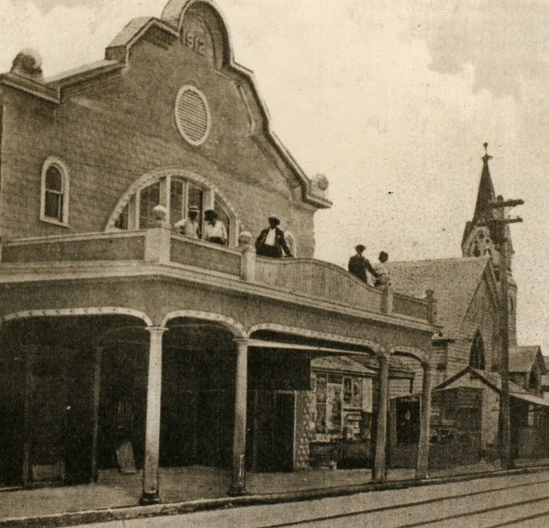 People standing on a balcony over a sidewalk