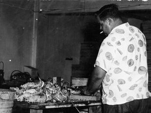 A man standing in front of a table covered in spiny lobster