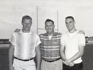 Three people on a field with goalposts in the background