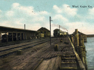 A postcard of a train approaching a station on the water. Text on the card reads Wharf, Knights Key Fla.