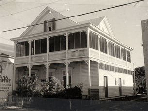 A three story wood-frame building with an enclosed porch on the second floor.