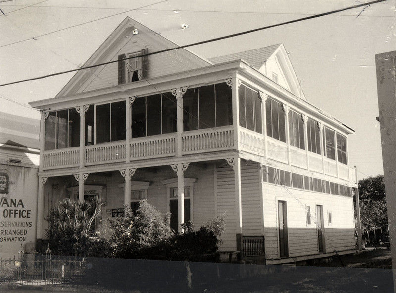 A three story wood frame building with an enclosed porch on the second floor.