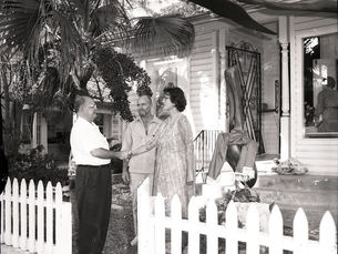 A man and woman shake hands, while another man looks on.