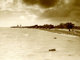 A beach with several cabanas and two towers in the distance