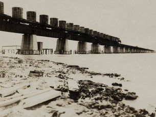 A train carrying large tanks goes over a bridge