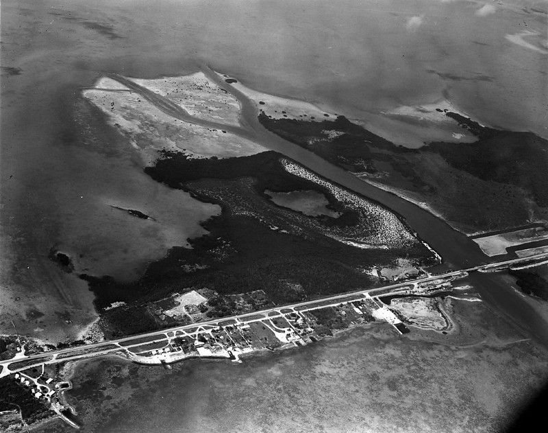 Aerial view of an island with a highway and some development
