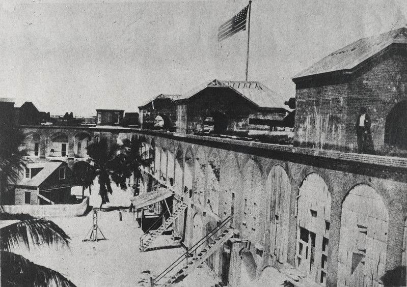 The inside of a fort with several sets of stairs leading to the second level and an American flag flying from the top.