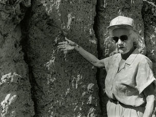 A woman gestures at a rock wall