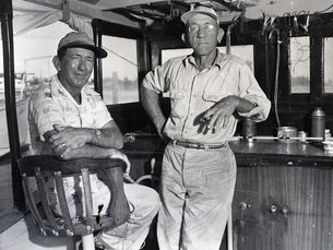 Two men inside the cabin of a boat.