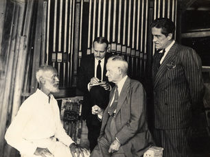 A man on the left sitting and facing three other men looking at him.