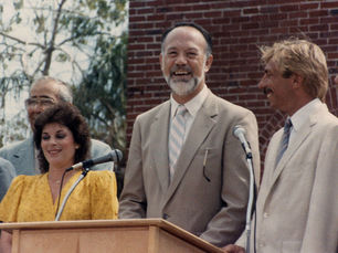 three people behind a lectern with microphones