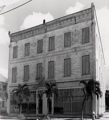 A three story building with shuttered windows and a storefront on the first floor with a sign that reads Long's.