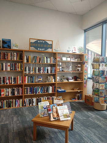 W book shelf with books and gifts as well as a table with displaye dbooks and a card rack.